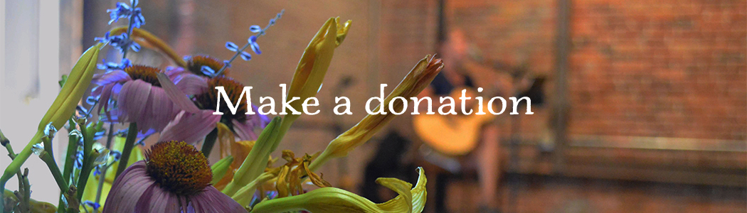 Flower bouquet closeup with blurred guitarist in front of brick wall, reads Make a donation 